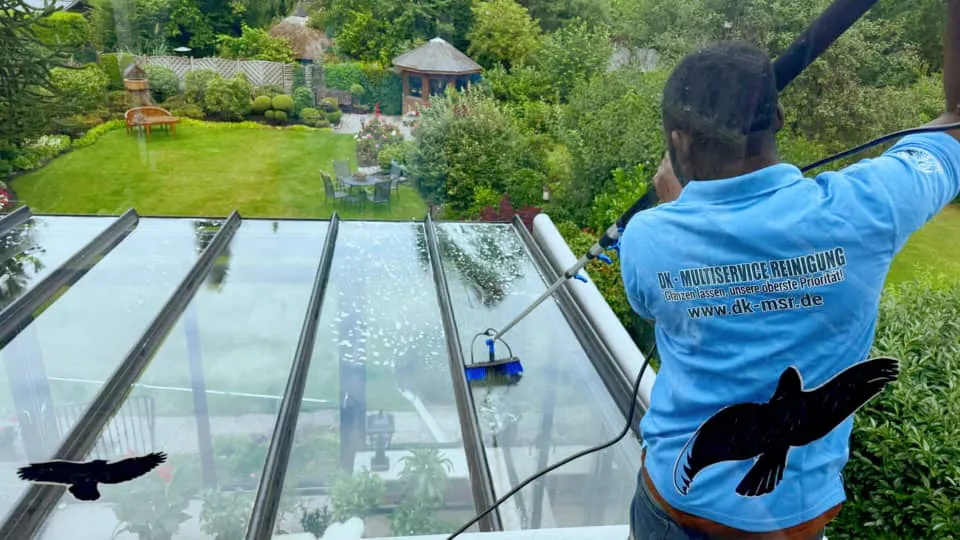 Ein Mann in einem blauen Hemd reinigt Glas auf einem Dach, um eine klare Sicht von oben zu gewährleisten.