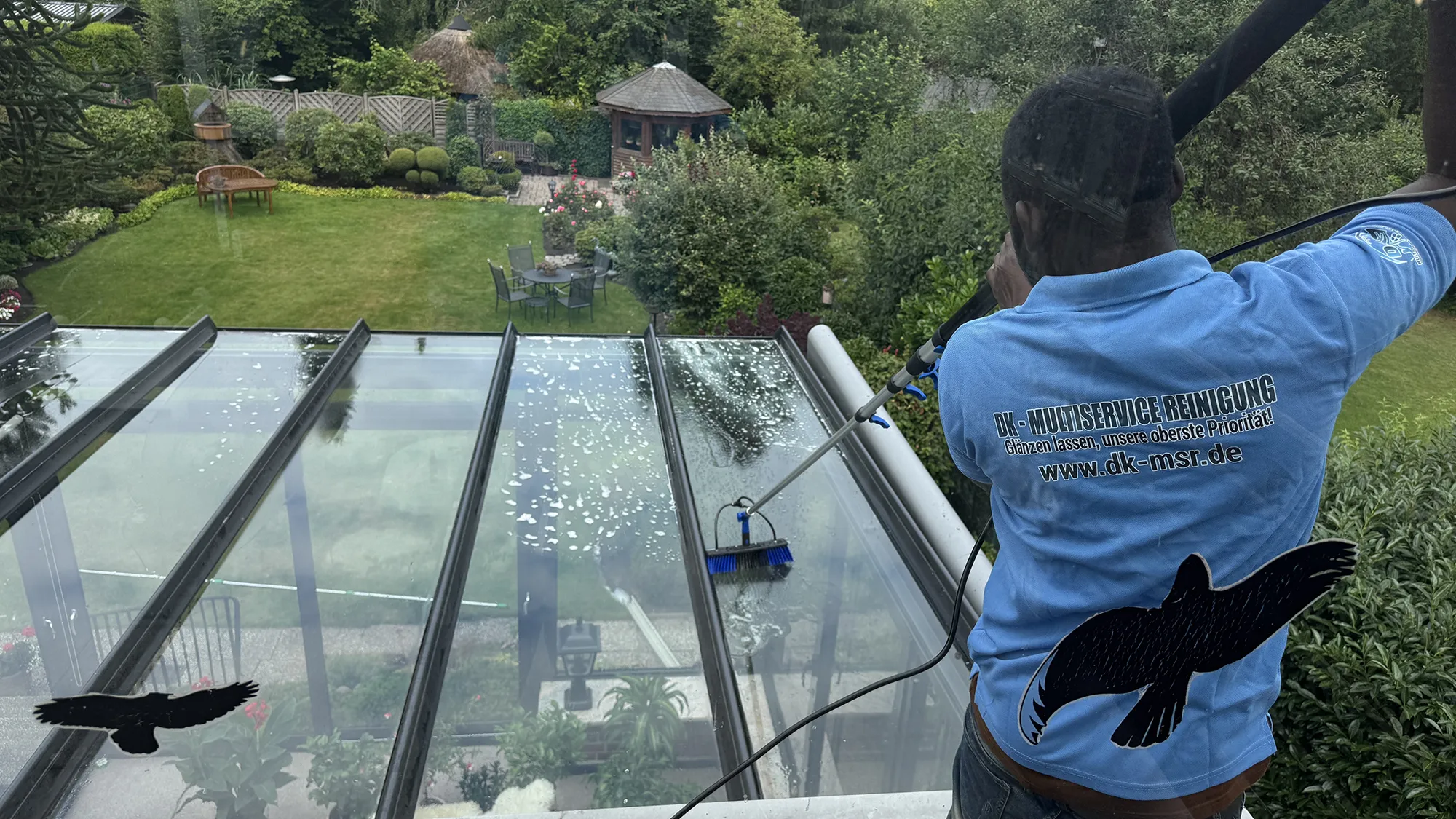 Ein Mann trägt ein blaues Hemd und putzt Glas auf einem Dach.
