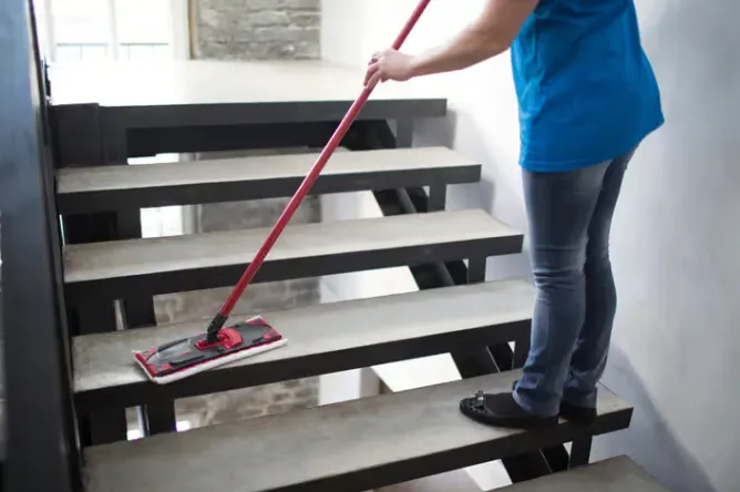 Jemand wischt die Treppen mit einem Mop sauber.
